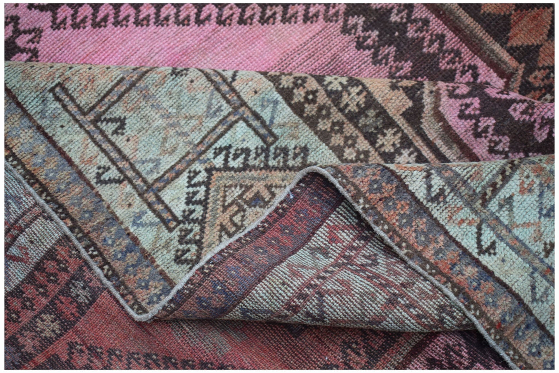 A vintage handwoven Persian Hamadan rug featuring a worn texture and a unique pink and blue palette.