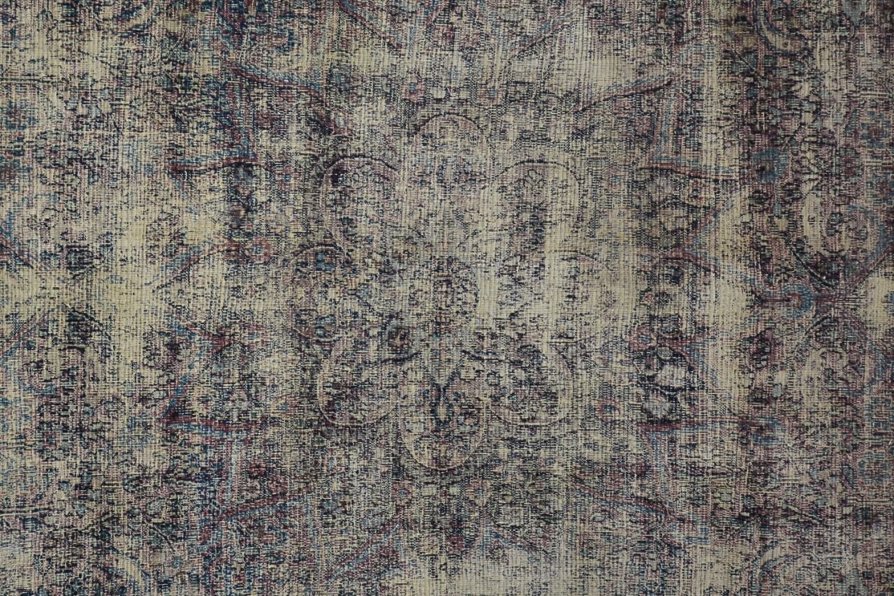 An antique Persian Kerman rug featuring a central medallion with intricate floral patterns.