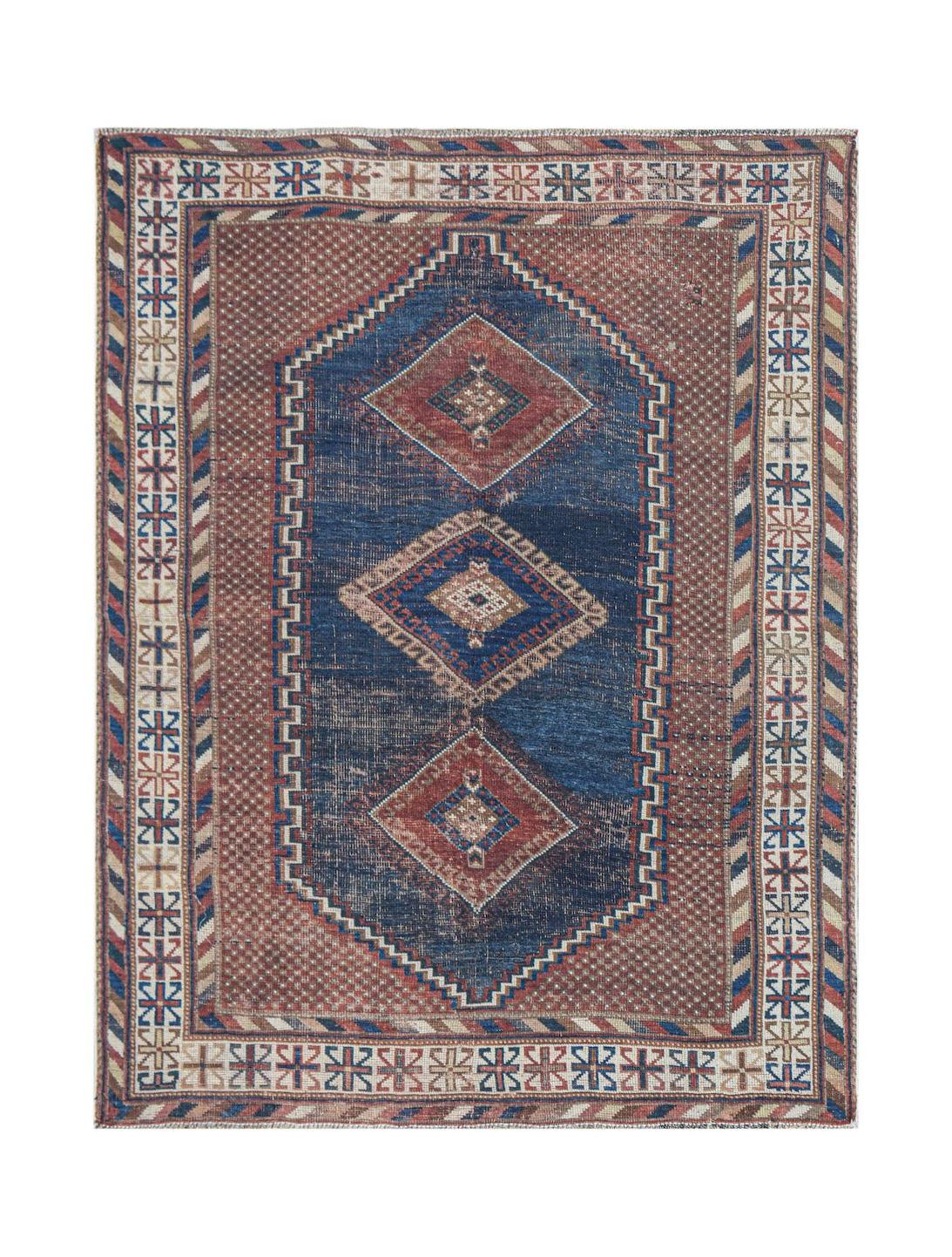 An antique handwoven Persian rug featuring a blue central medallion on a patterned brown field.