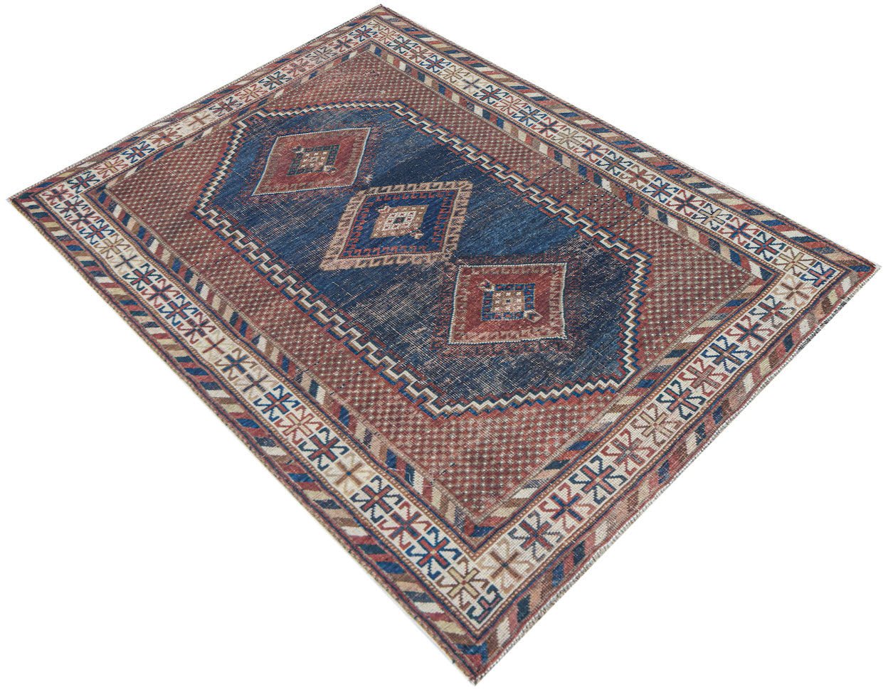 An antique handwoven Persian rug featuring a blue central field with geometric diamond motifs.