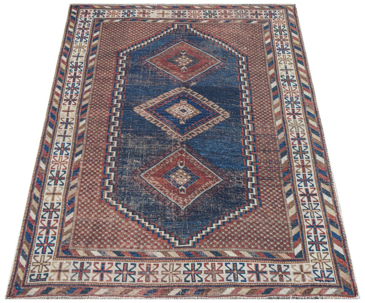 Antique Persian rug with a central blue diamond motif and geometric borders.