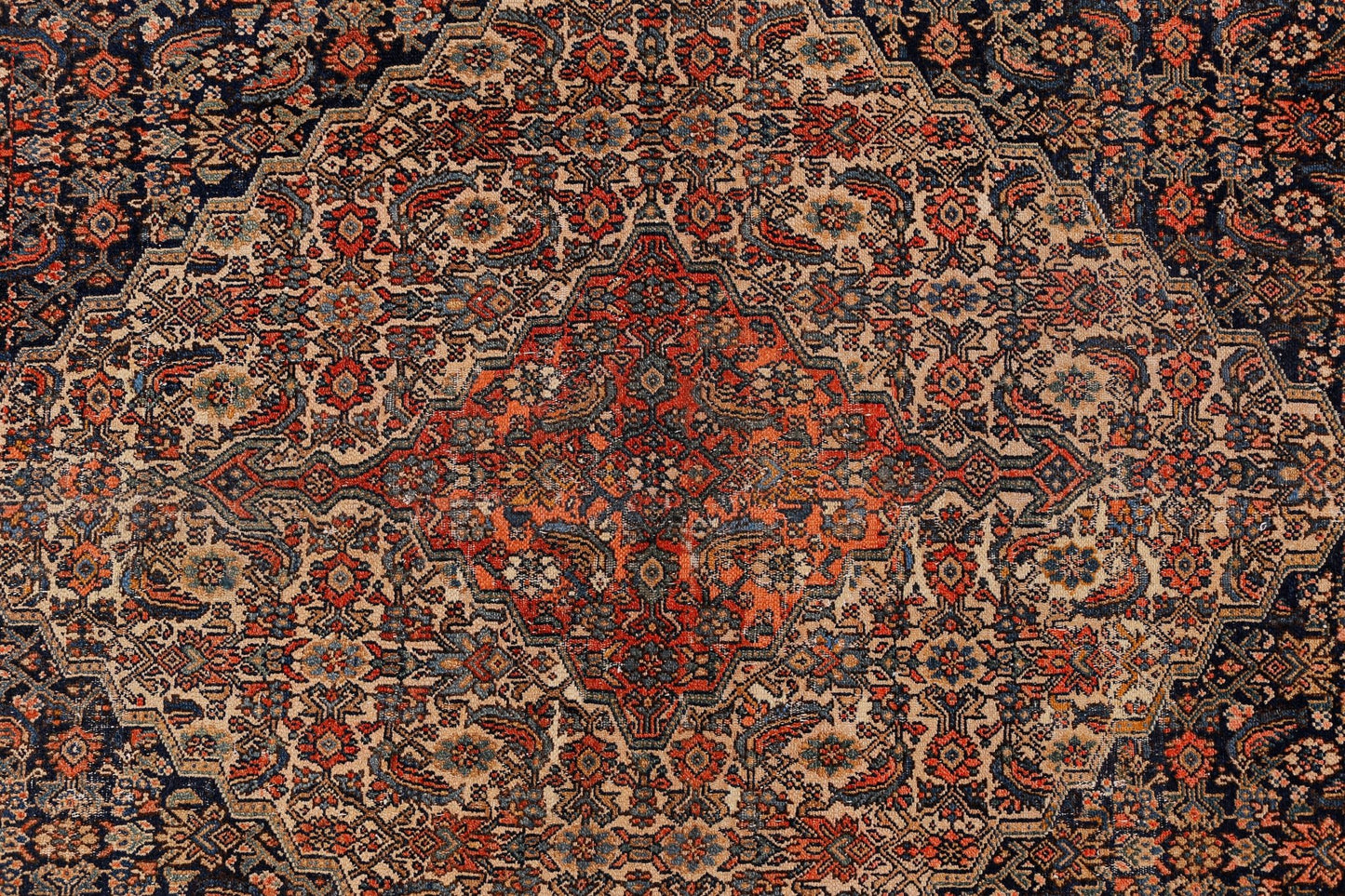 An antique Persian Senneh rug featuring a detailed geometric medallion in red, blue, and beige.