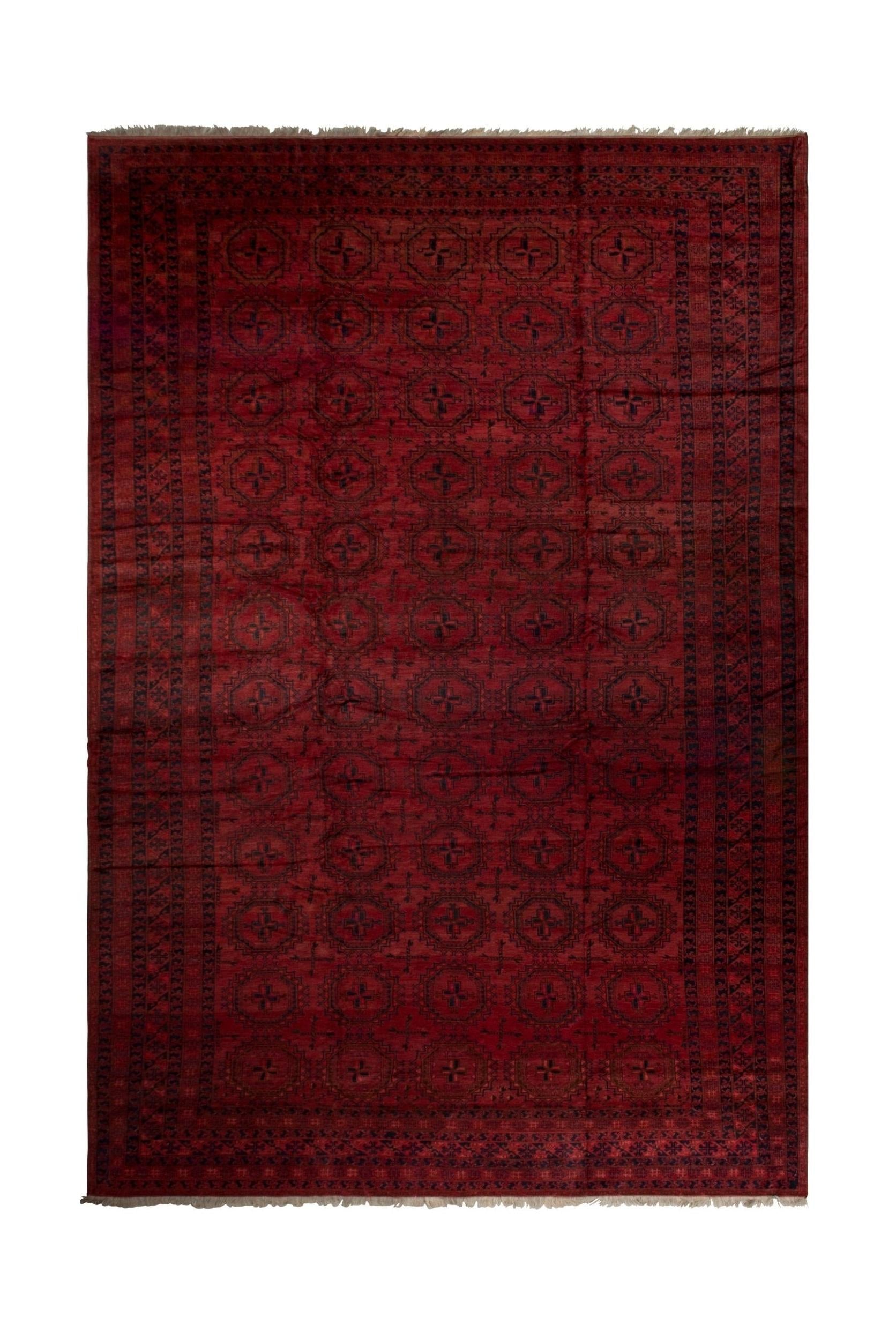 An antique Afghan Turkmen rug featuring a deep red field with repeating geometric motifs.