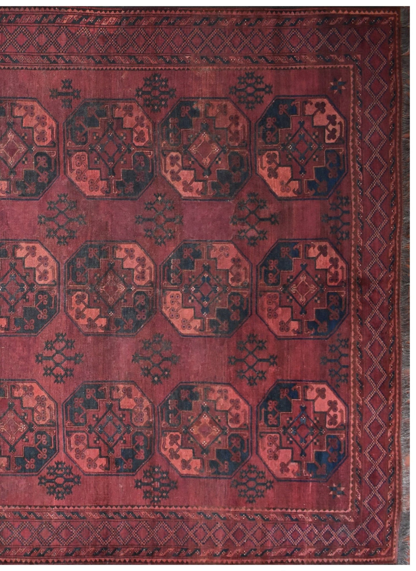 An antique Afghan Turkmen rug featuring a repeating geometric octagonal pattern in red and blue.