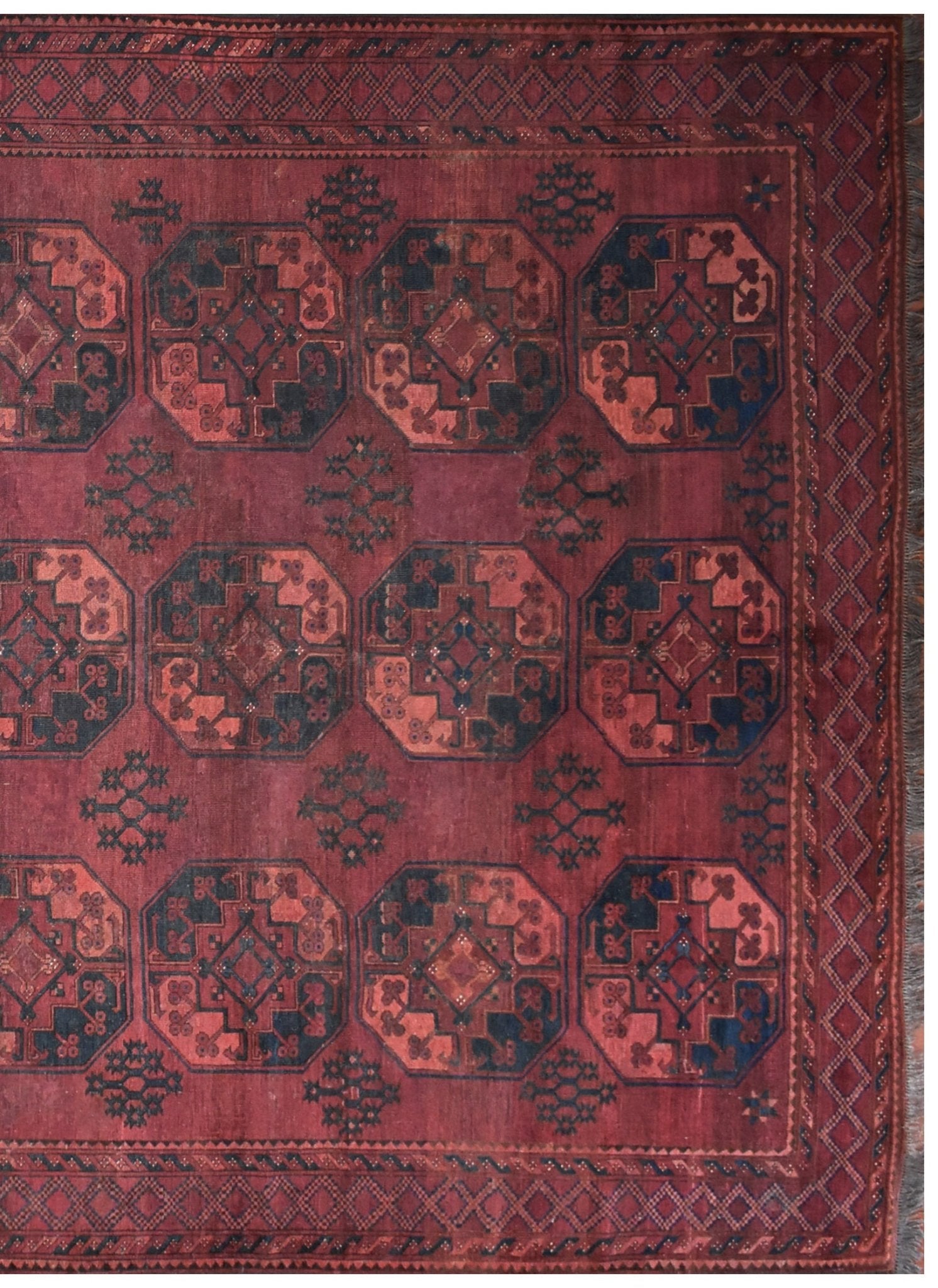 An antique Afghan Turkmen rug featuring a repeating geometric octagonal pattern in red and blue.