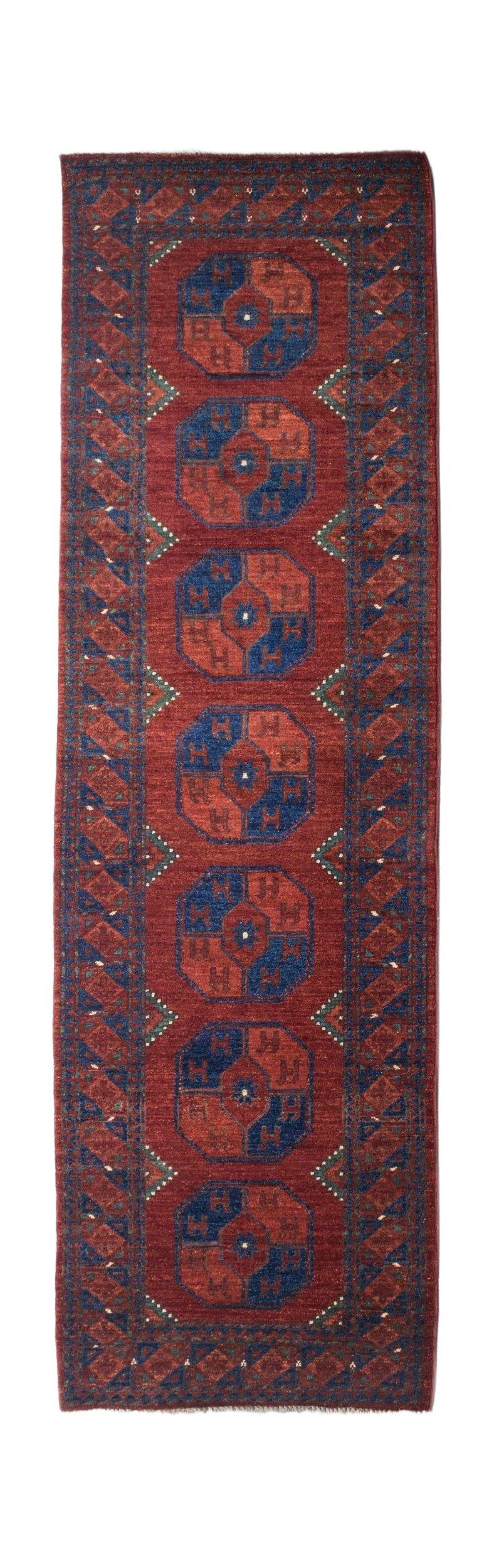 Handmade Afghan Chobi runner rug featuring a repeating geometric medallion pattern in red and blue.