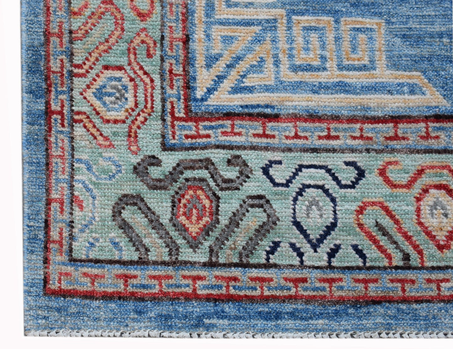 A corner detail of a handwoven Afghan Chobi rug featuring intricate geometric and floral patterns.