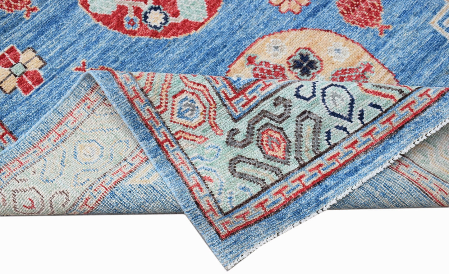 A handwoven Afghan Chobi rug in blue with traditional circular motifs and a folded corner.