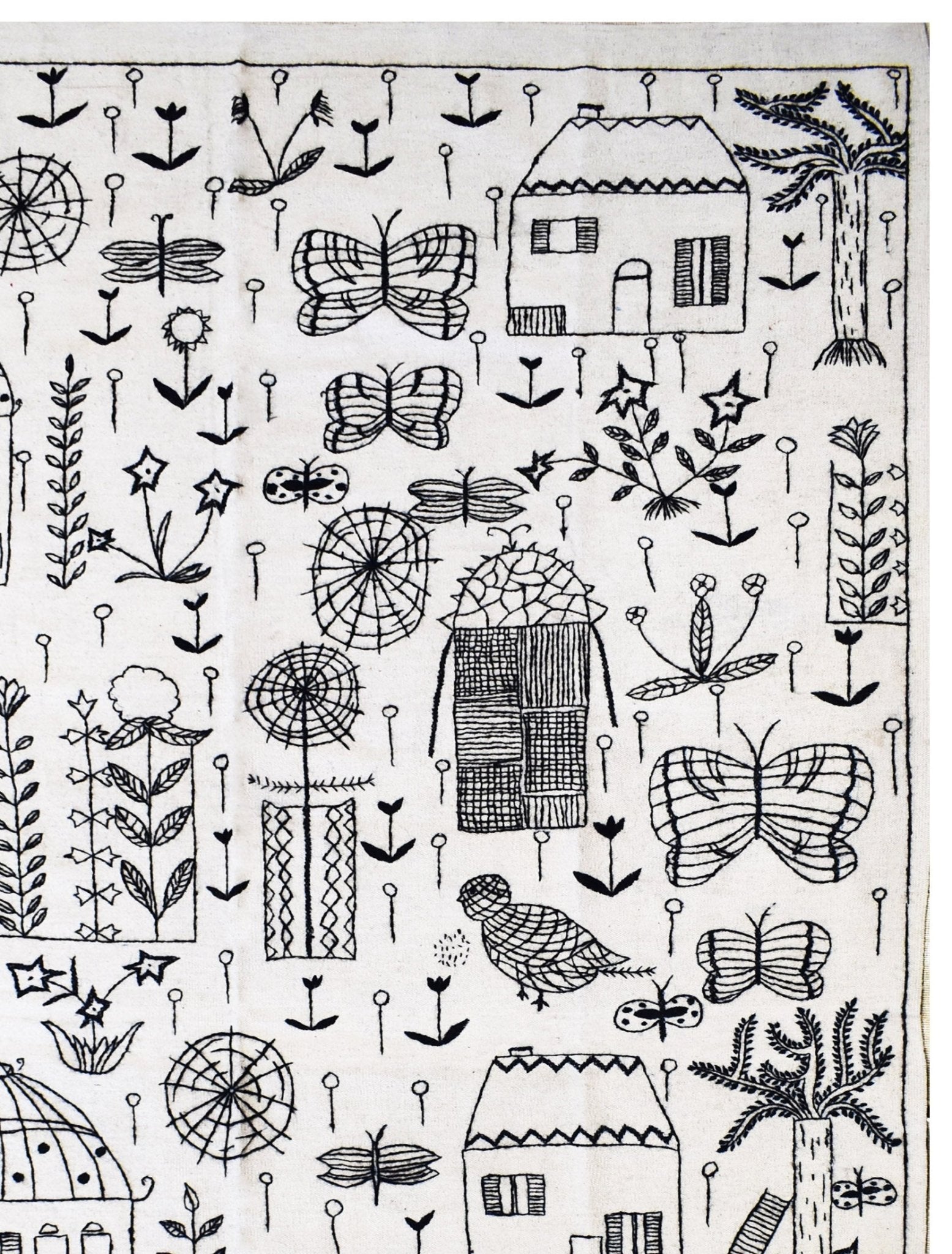 Handmade wool kilim featuring black embroidered folk art motifs of houses, butterflies, and plants.