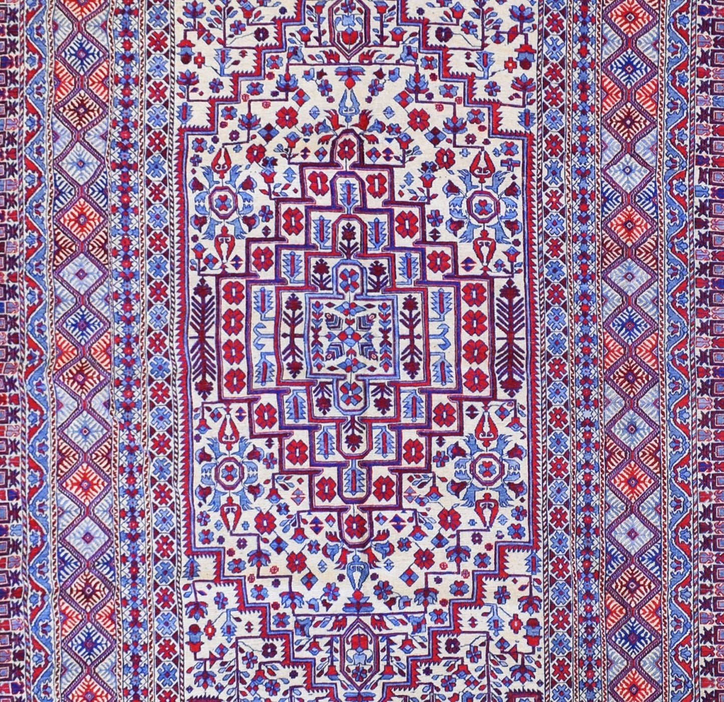 A vintage Afghan wool kilim featuring intricate geometric patterns in red, blue, and cream.