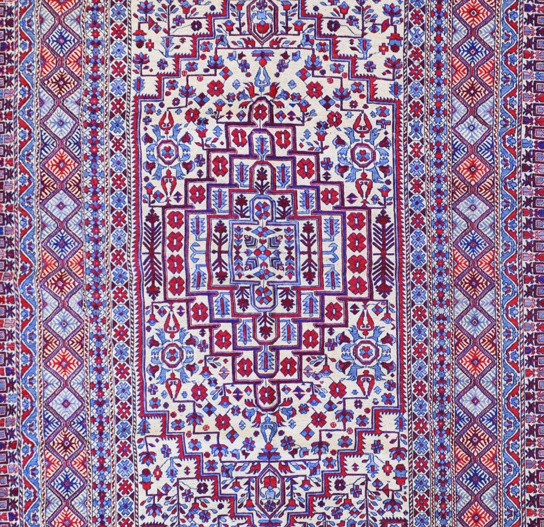 A vintage Afghan wool kilim featuring intricate geometric patterns in red, blue, and cream.
