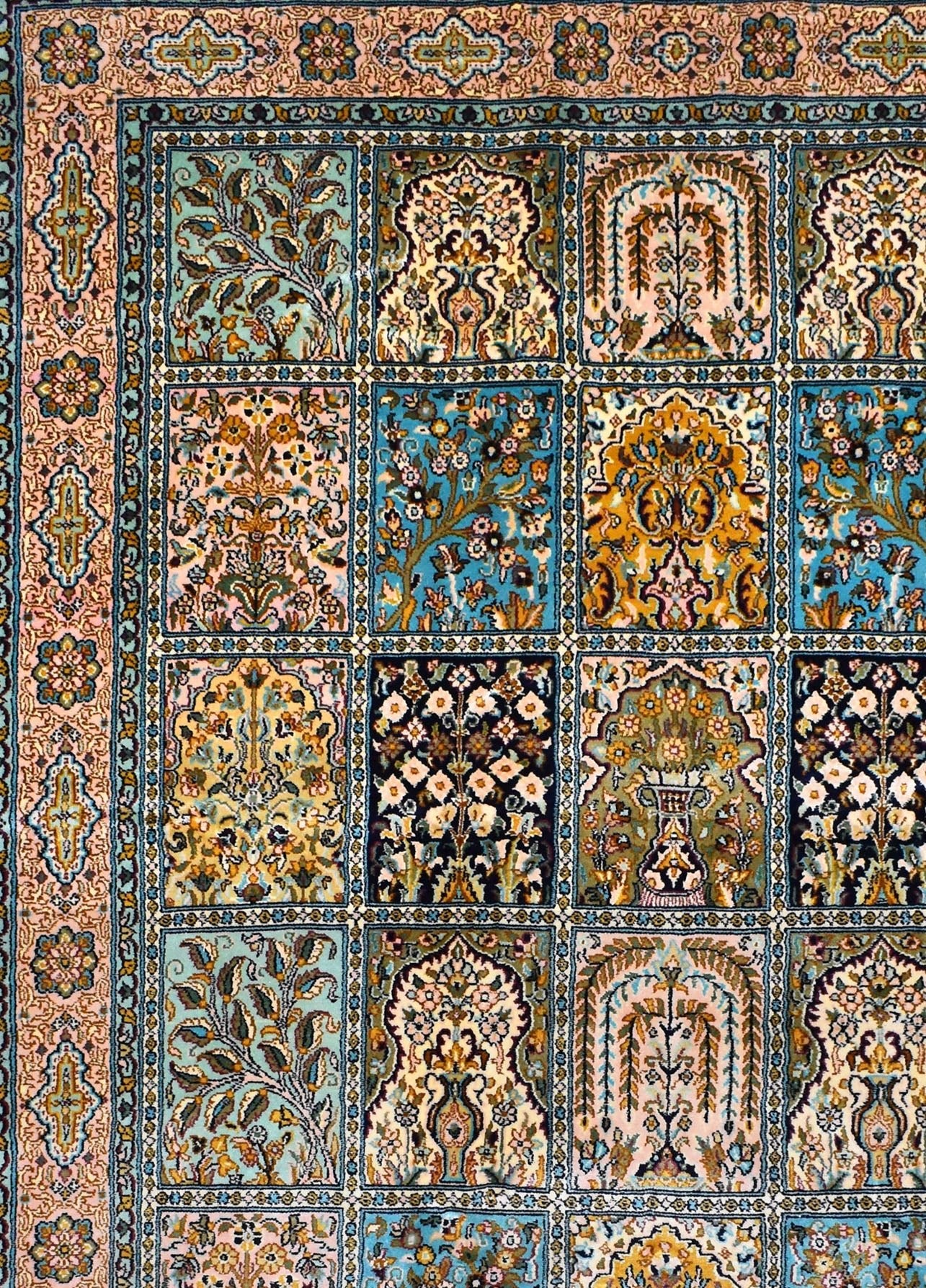 A handmade Kashmiri silk rug featuring a grid of intricate floral and garden motifs.