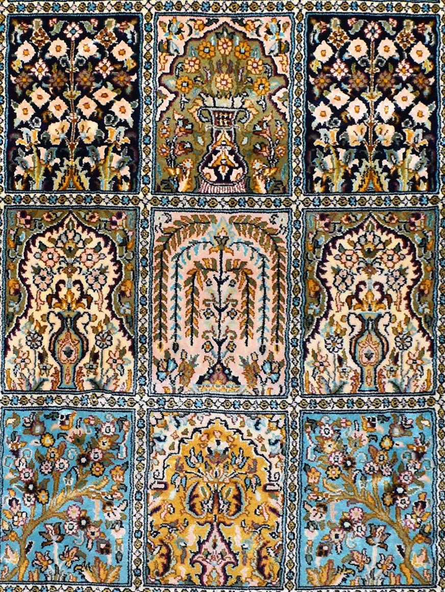 A handmade Kashmiri silk rug featuring a grid of intricate floral and vase motifs in vibrant colors.