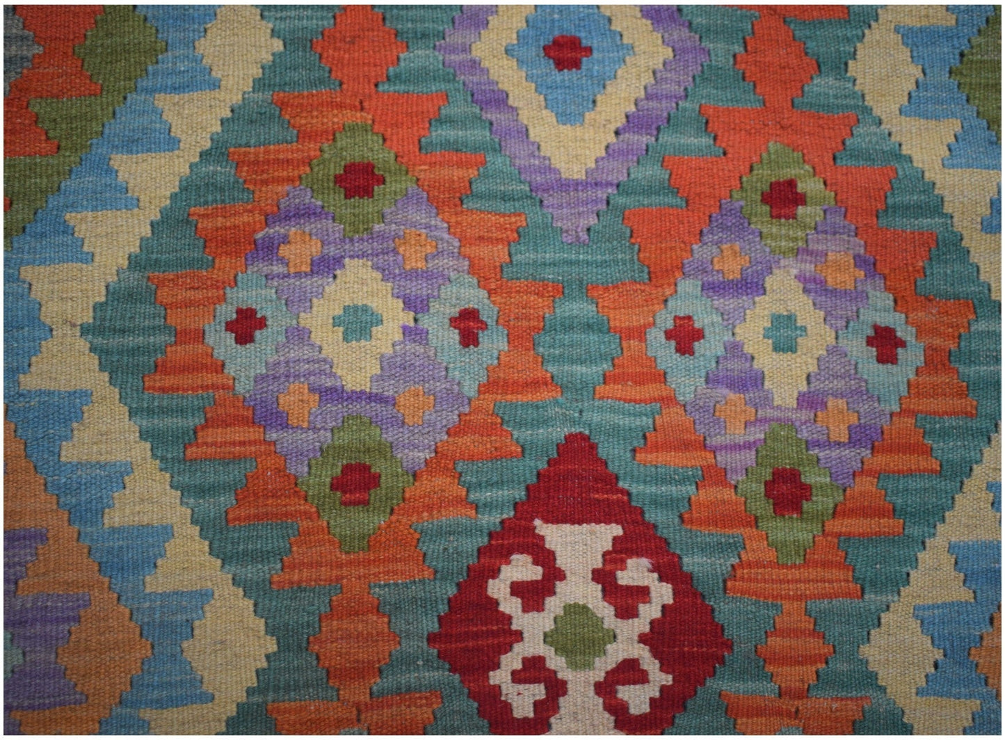 Handmade Afghan Maimana kilim runner featuring a vibrant geometric pattern in wool.
