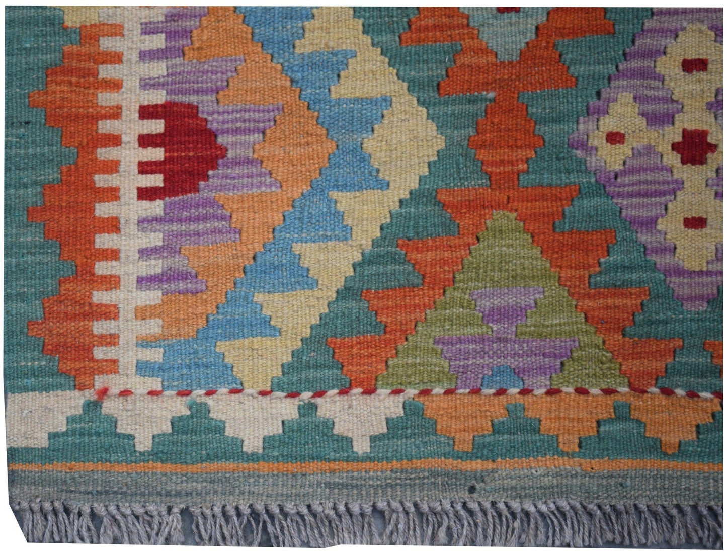 Handmade Afghan Maimana kilim runner featuring a colorful geometric pattern and fringed edges.