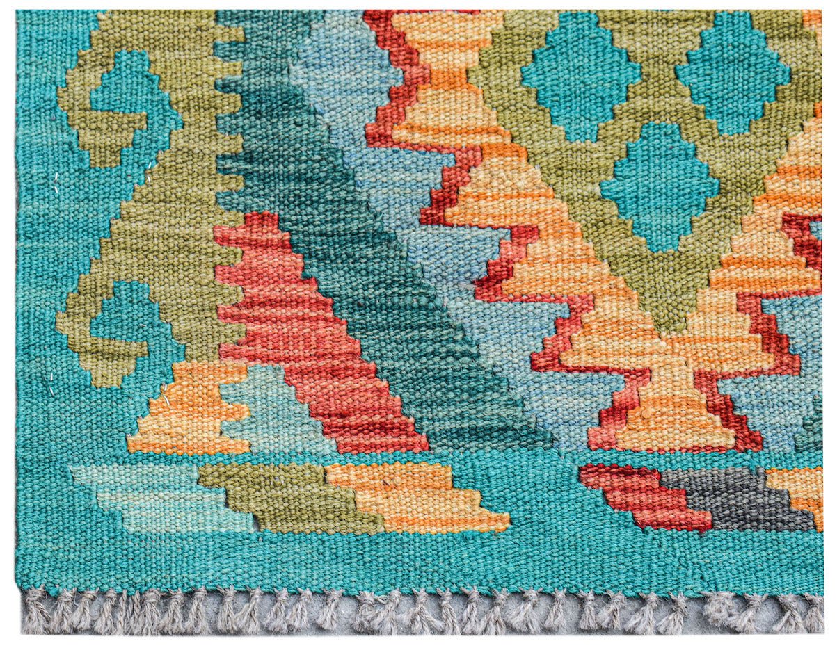 Close-up of a colorful, geometric Afghan Maimana Kilim rug with fringe.