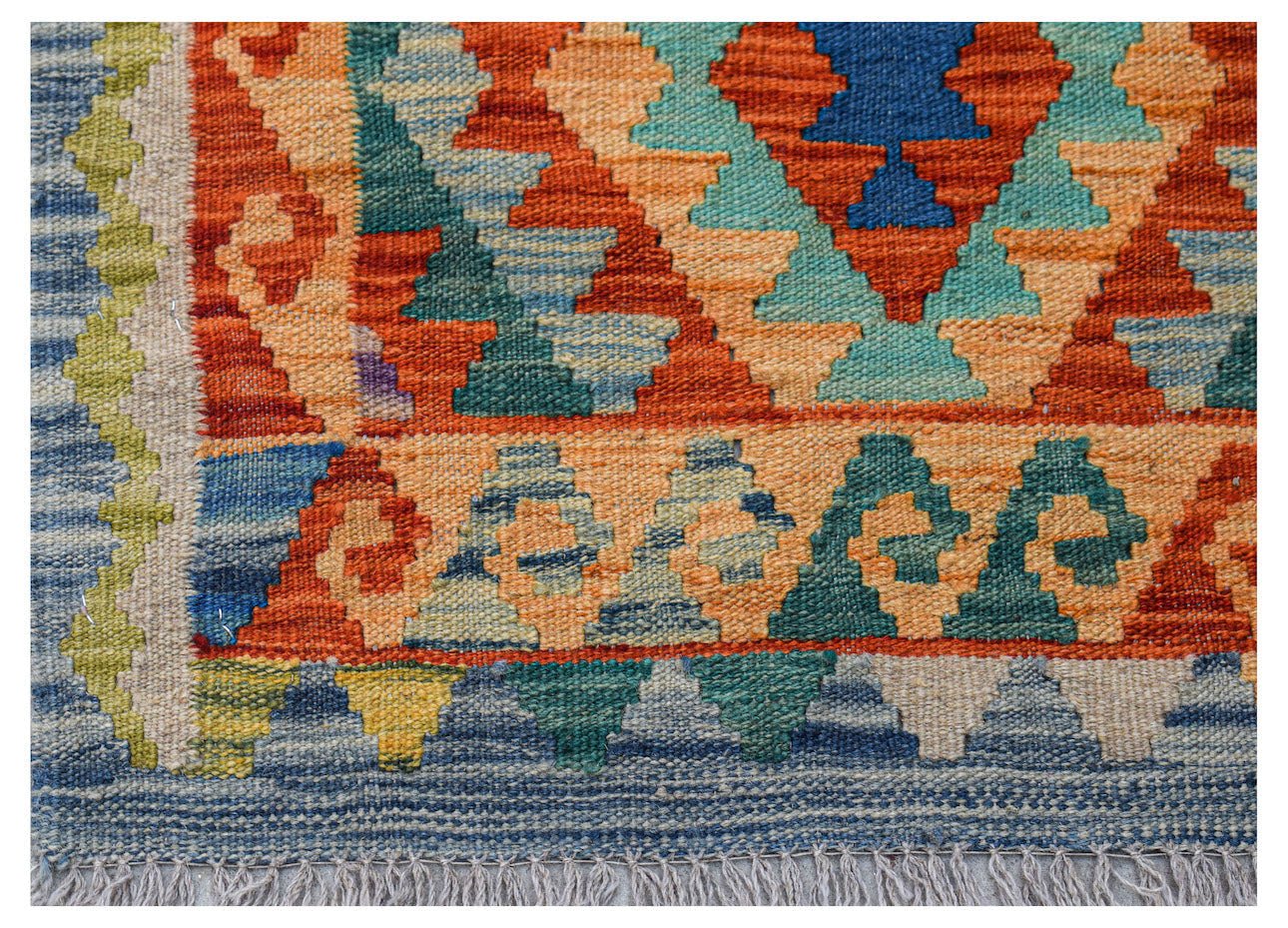 A handwoven Afghan Maimana kilim rug featuring a geometric pattern in vibrant orange and blue tones.
