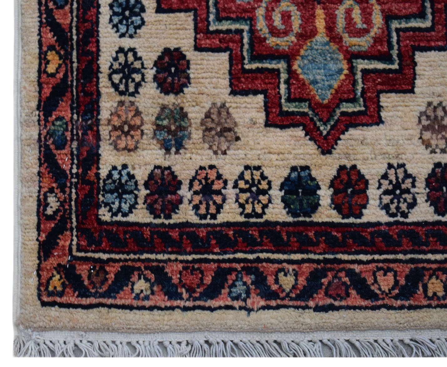 A handmade Afghan Chobi rug featuring a geometric red medallion on a cream field with fringe.