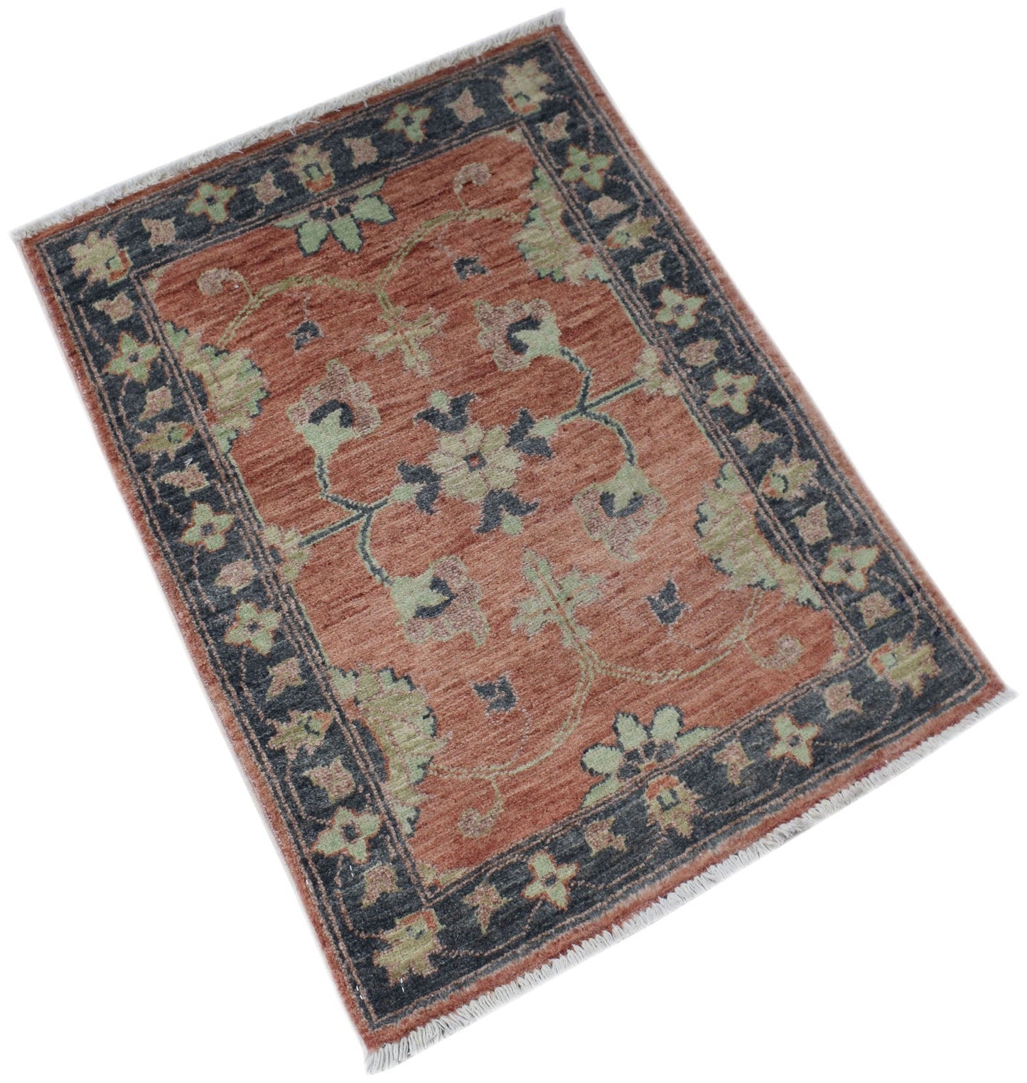 A handmade Afghan Chobi rug featuring a floral pattern in rust, sage green, and charcoal grey.