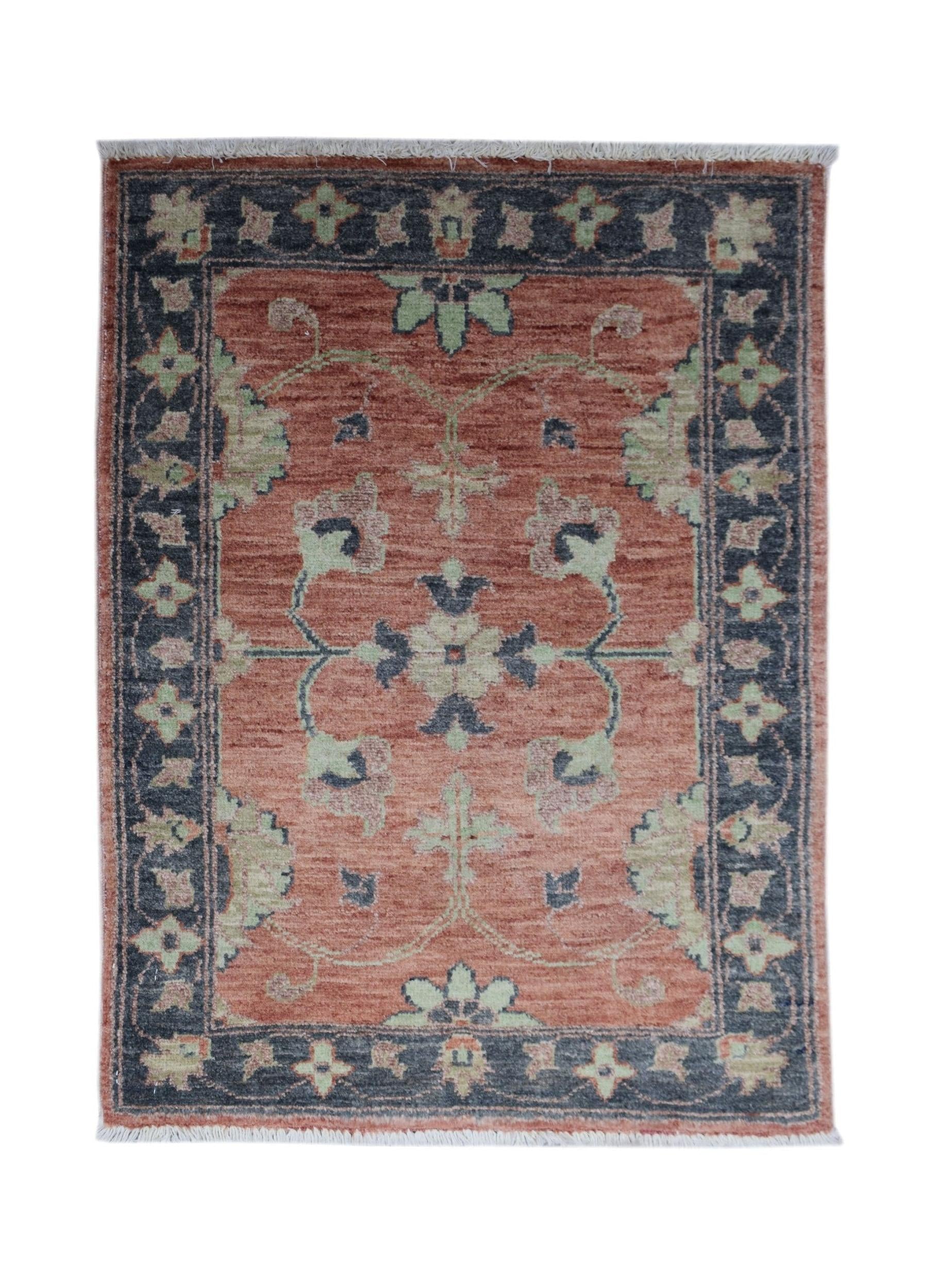 A handmade mini Afghan Chobi rug featuring a floral pattern in rust, sage green, and charcoal.