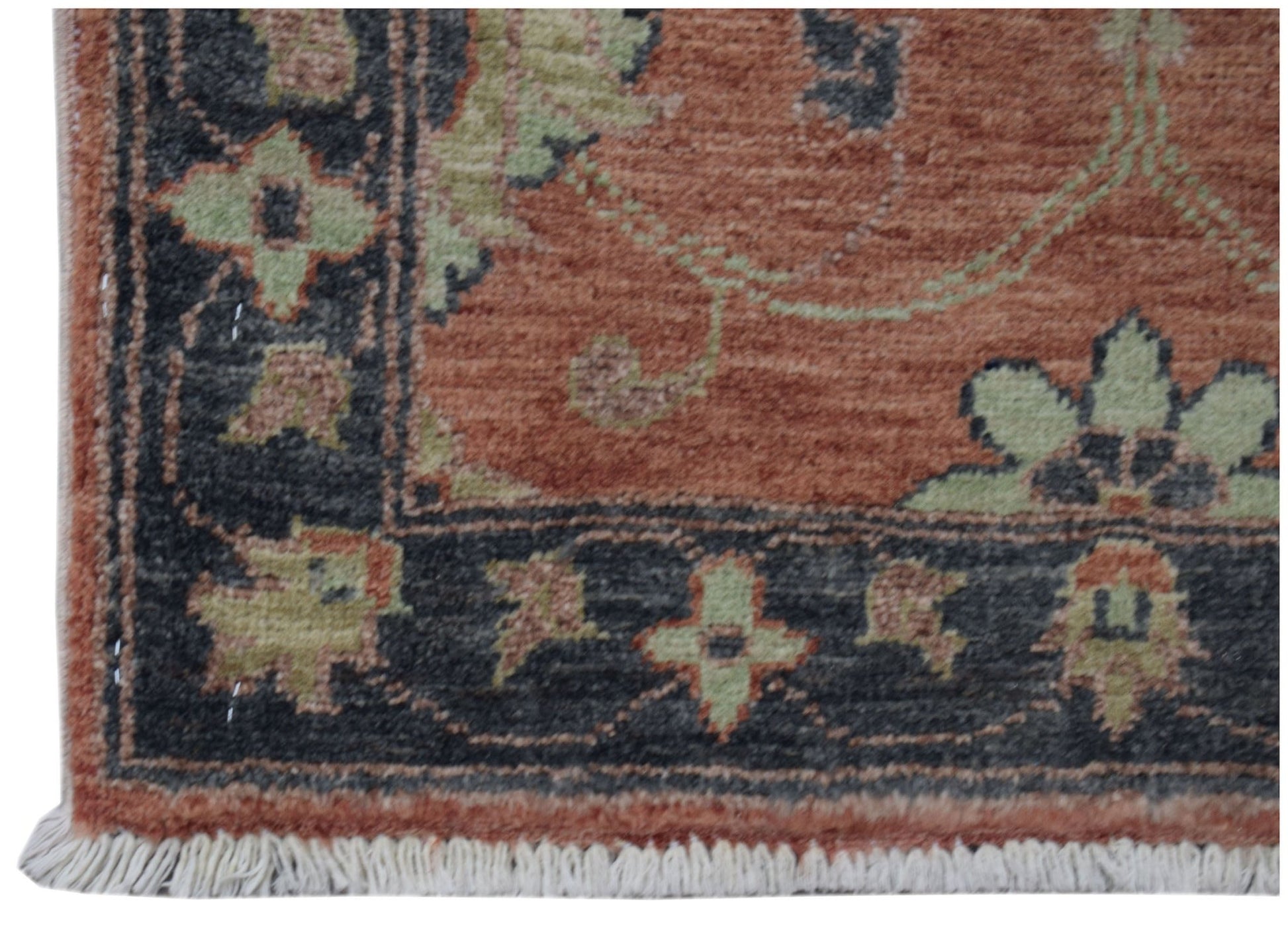 A handmade Afghan Chobi rug featuring a terracotta field with green floral patterns and a dark border.