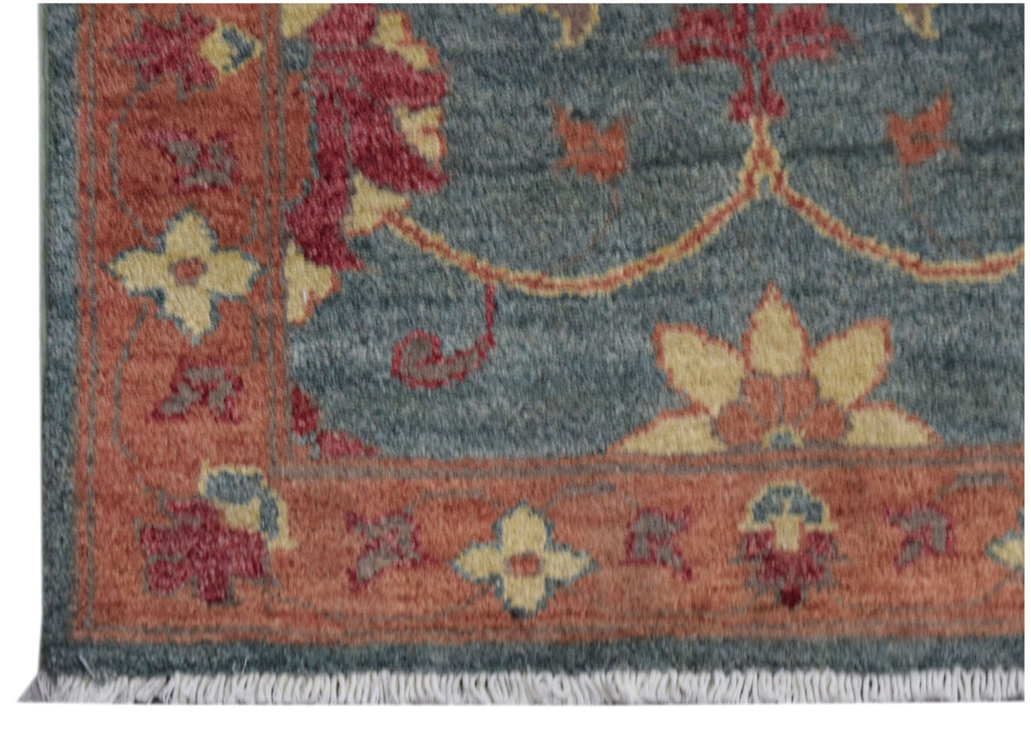A handmade Afghan Chobi rug featuring a blue field with floral patterns and a rust-colored border.