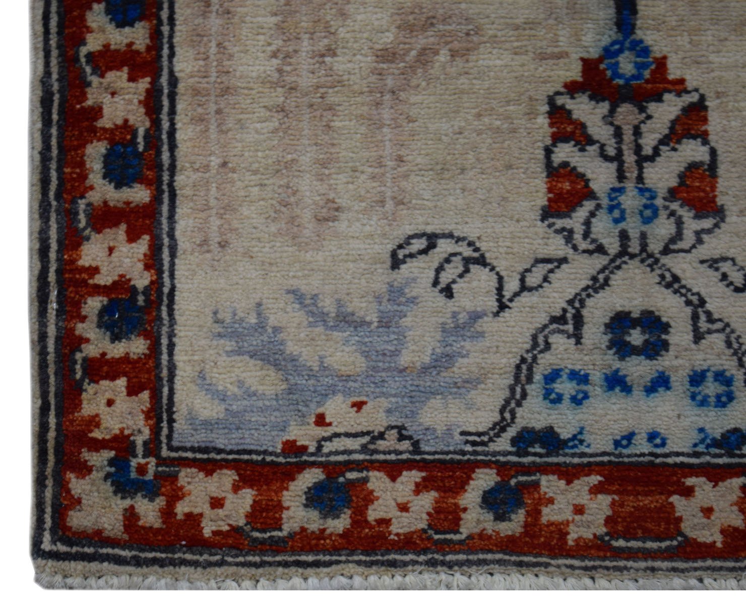 A corner view of a handmade Afghan Chobi rug featuring a red border and floral motifs on cream wool.