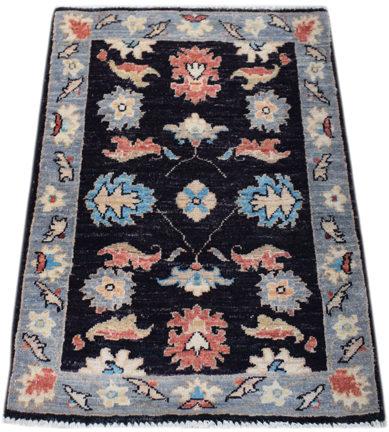 A handmade mini Afghan Chobi rug featuring a floral pattern in blue, red, and cream on black.