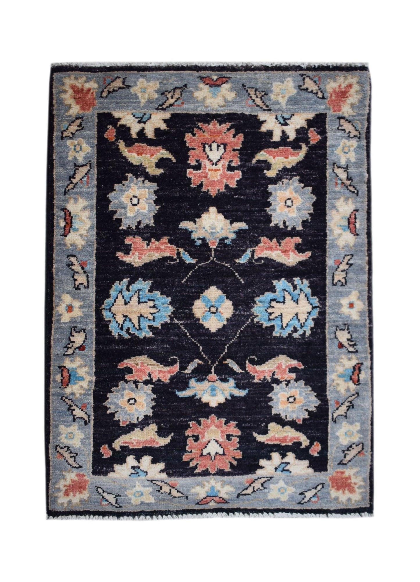 A handmade Afghan Chobi rug featuring a dark blue field with floral patterns and a light blue border.