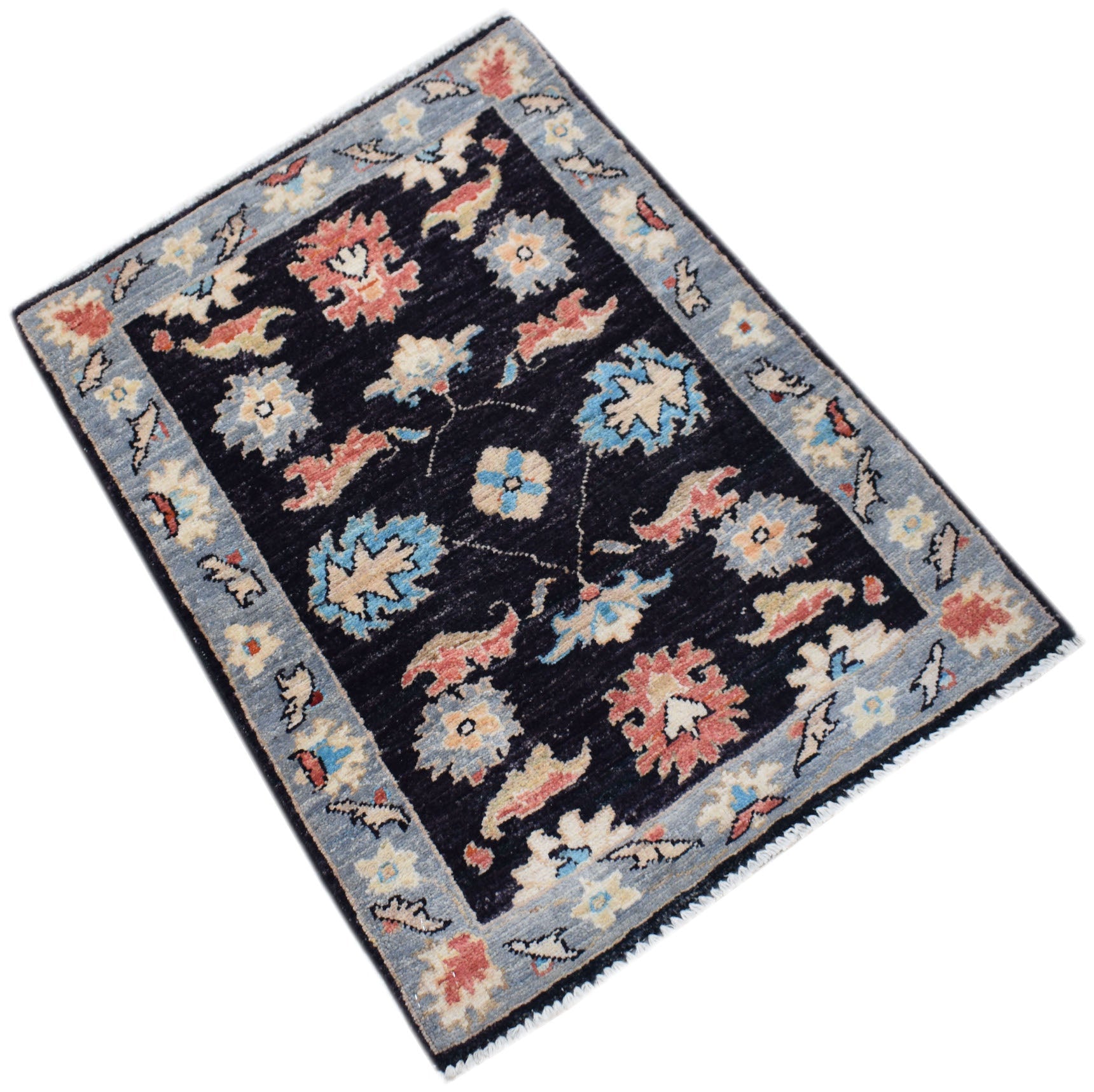 A handmade Afghan Chobi rug featuring a dark field with floral patterns and a light blue border.