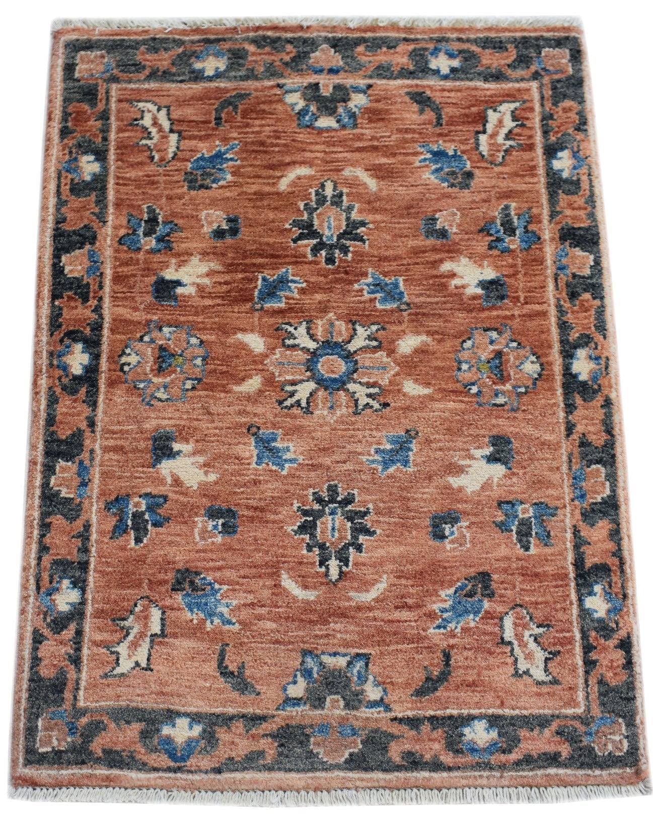 A handmade Afghan Chobi rug featuring a floral pattern in blue and cream on a terracotta background.