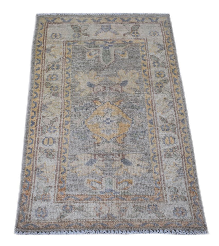 A handmade mini Afghan Chobi rug featuring a central yellow medallion on a grey field.