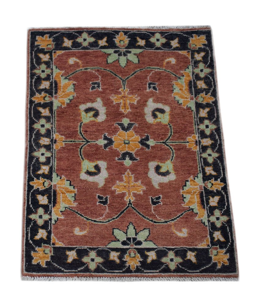 A handmade wool Afghan Chobi rug featuring a floral pattern in rust, black, and yellow tones.