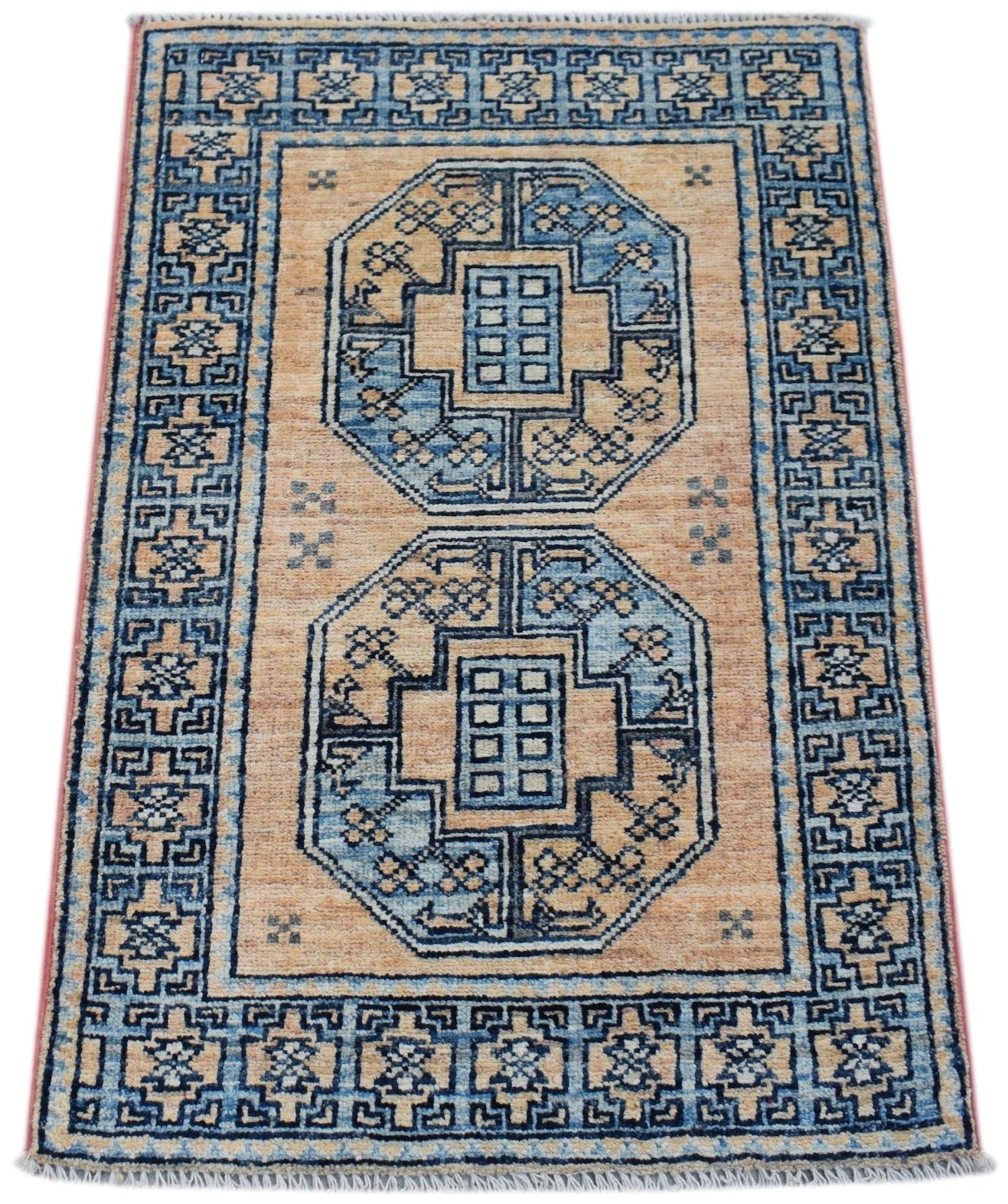 A handmade Afghan Chobi rug featuring two blue octagonal medallions on a tan wool field.
