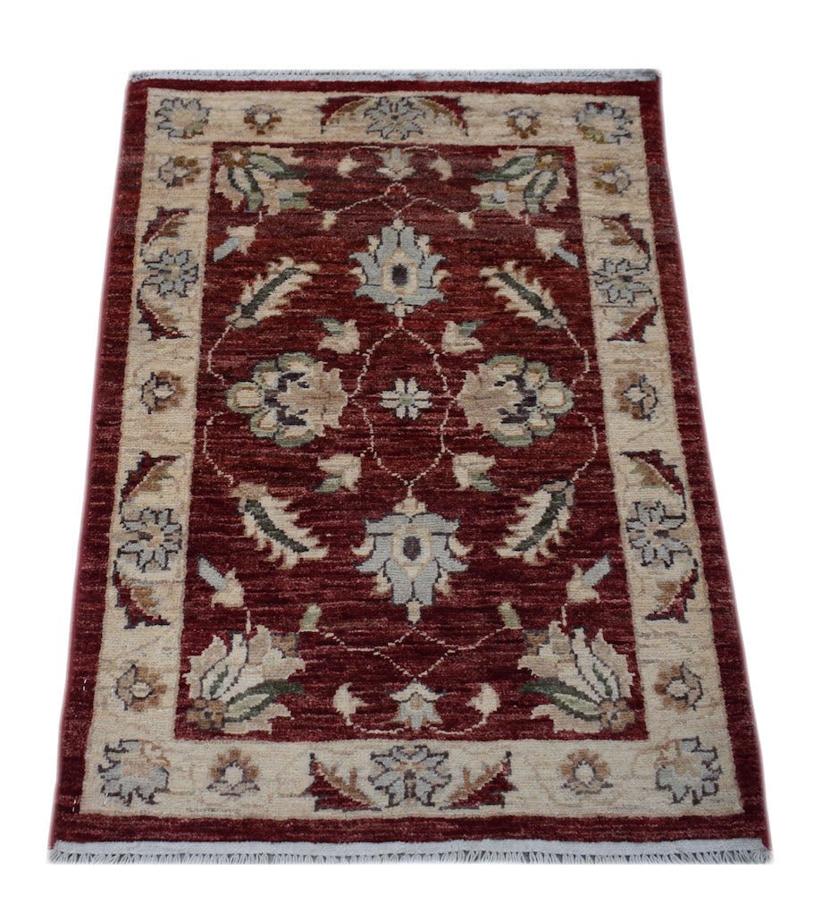 A rectangular handmade Afghan Chobi rug featuring a floral pattern in red and beige tones.