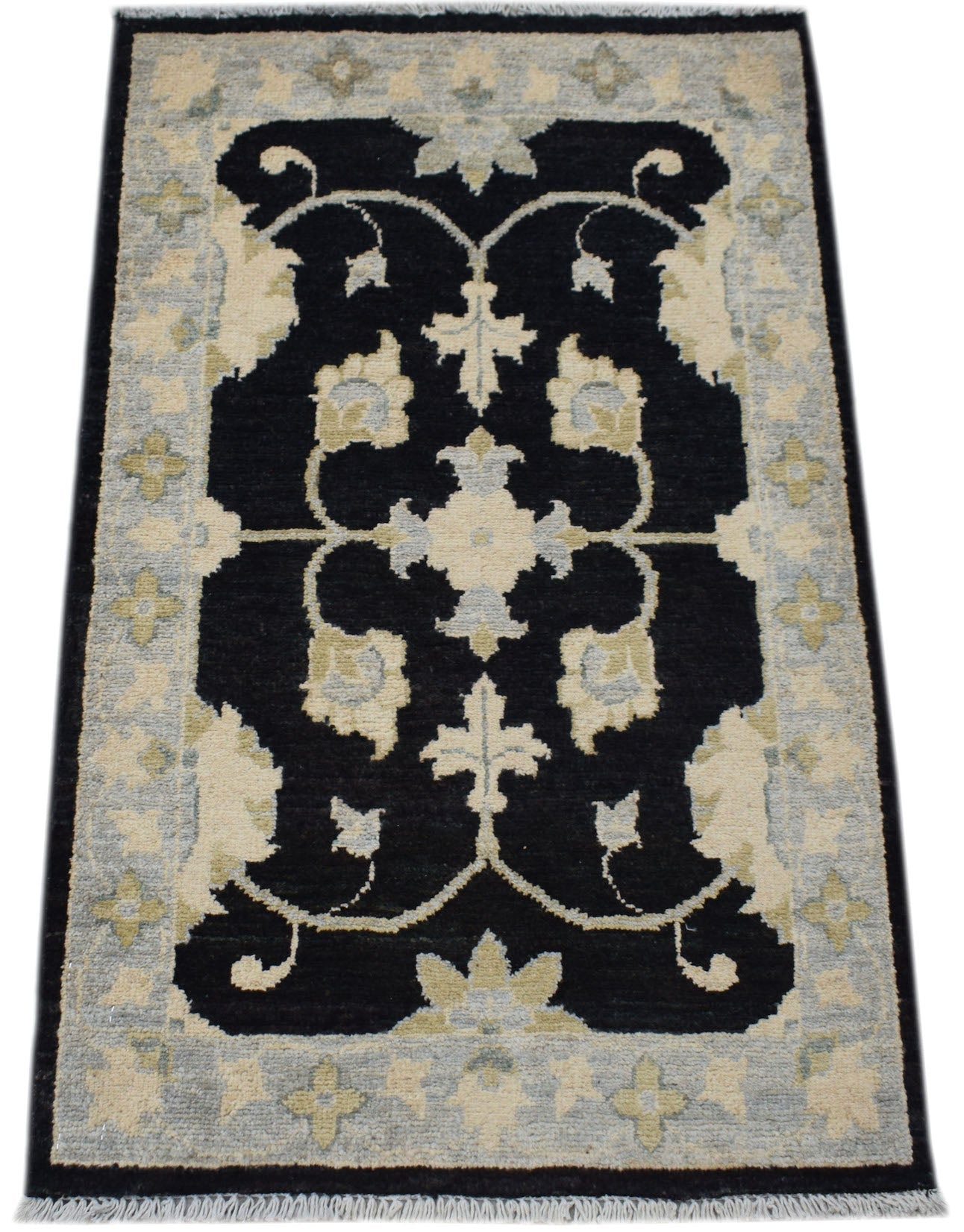 A rectangular handmade Afghan Chobi rug featuring a black central floral motif on a light border.