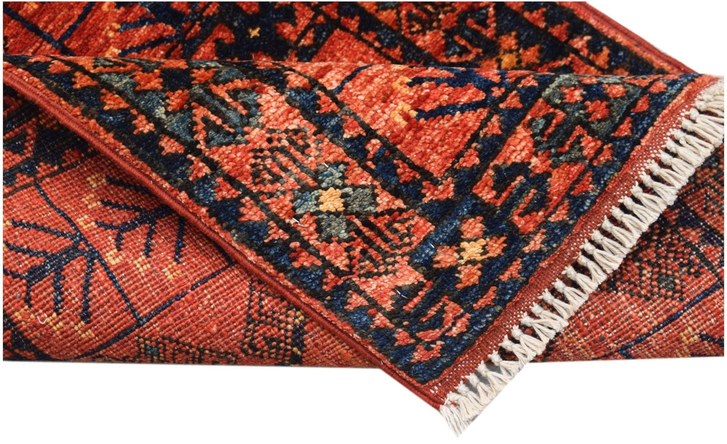 A folded handmade Afghan Chobi rug featuring a traditional red and blue geometric pattern.