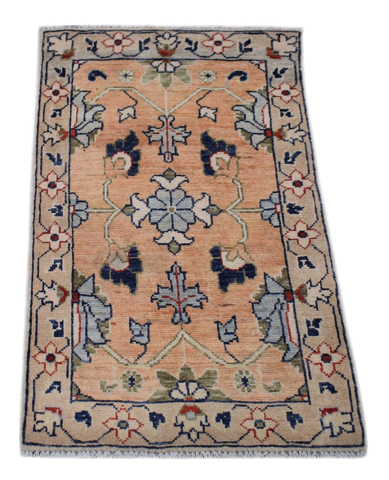 A handmade Afghan Chobi rug featuring a floral pattern in blue and cream on a peach background.