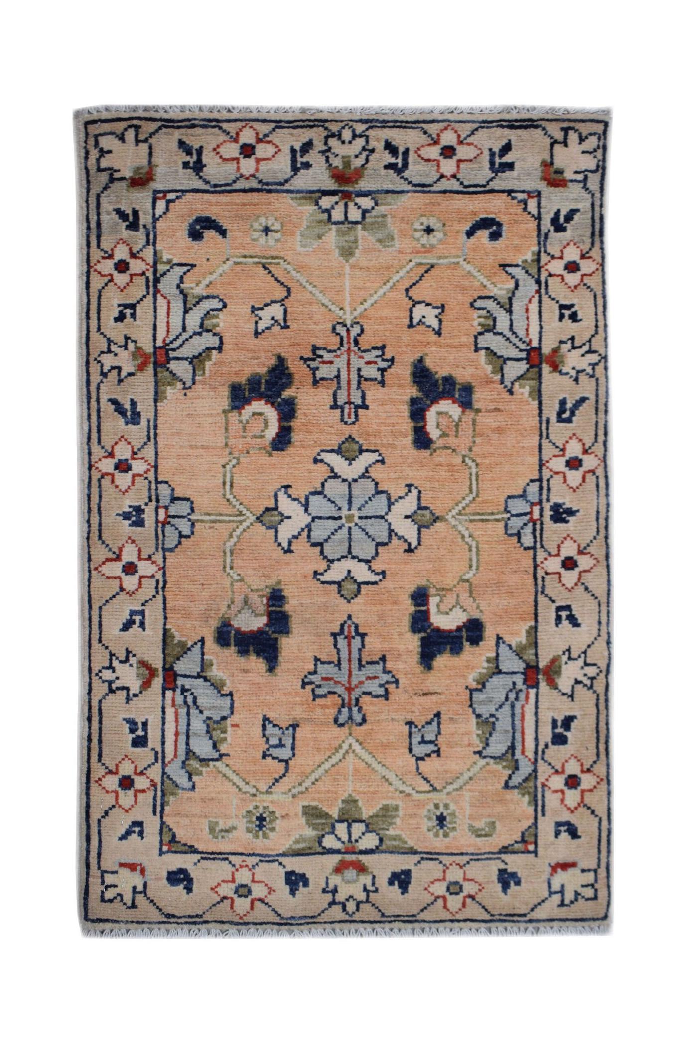 A handmade Afghan Chobi rug featuring a floral pattern in blue and red on a peach background.