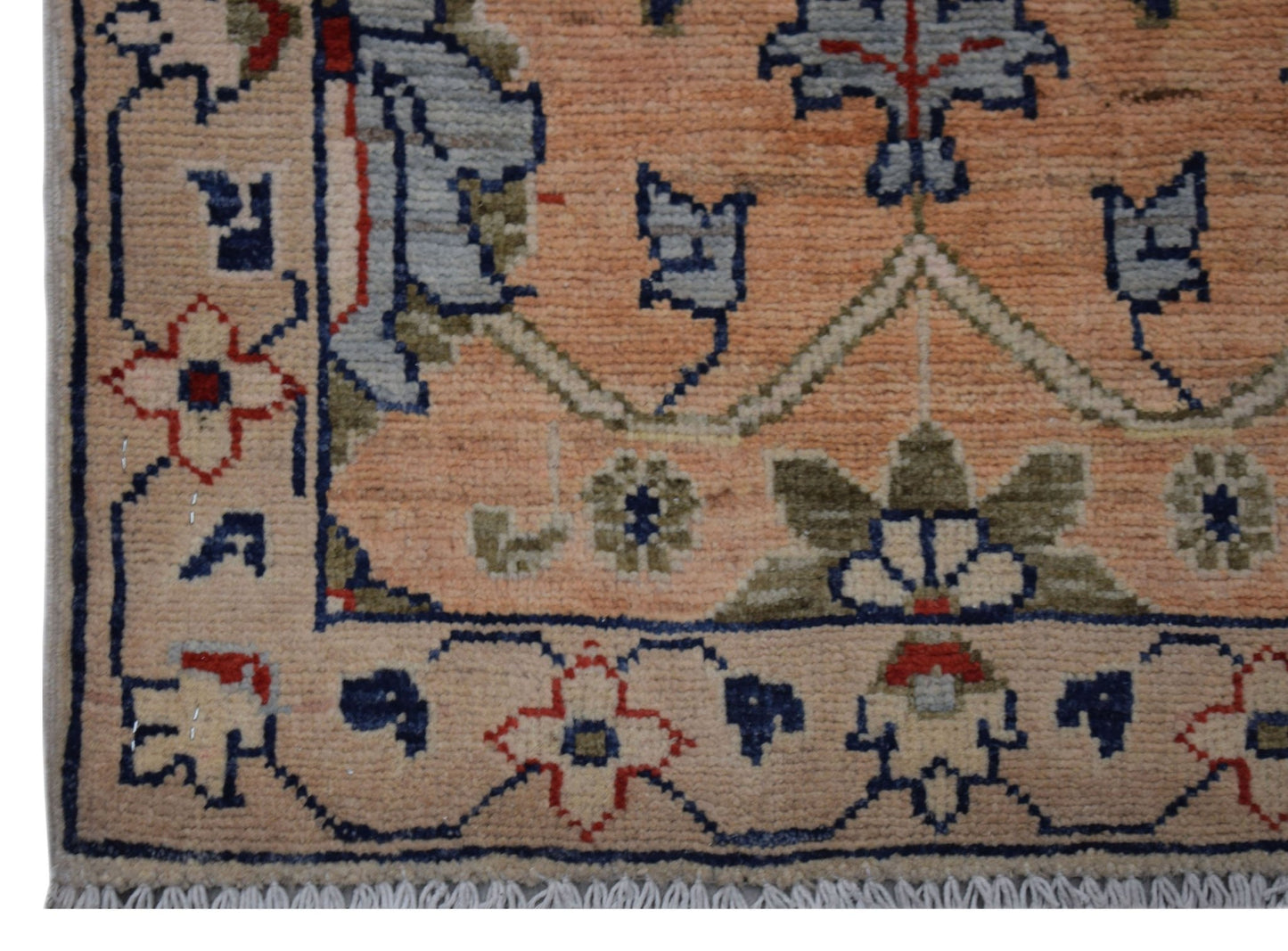 A handmade Afghan Chobi rug featuring a floral pattern in shades of peach, blue, and green.