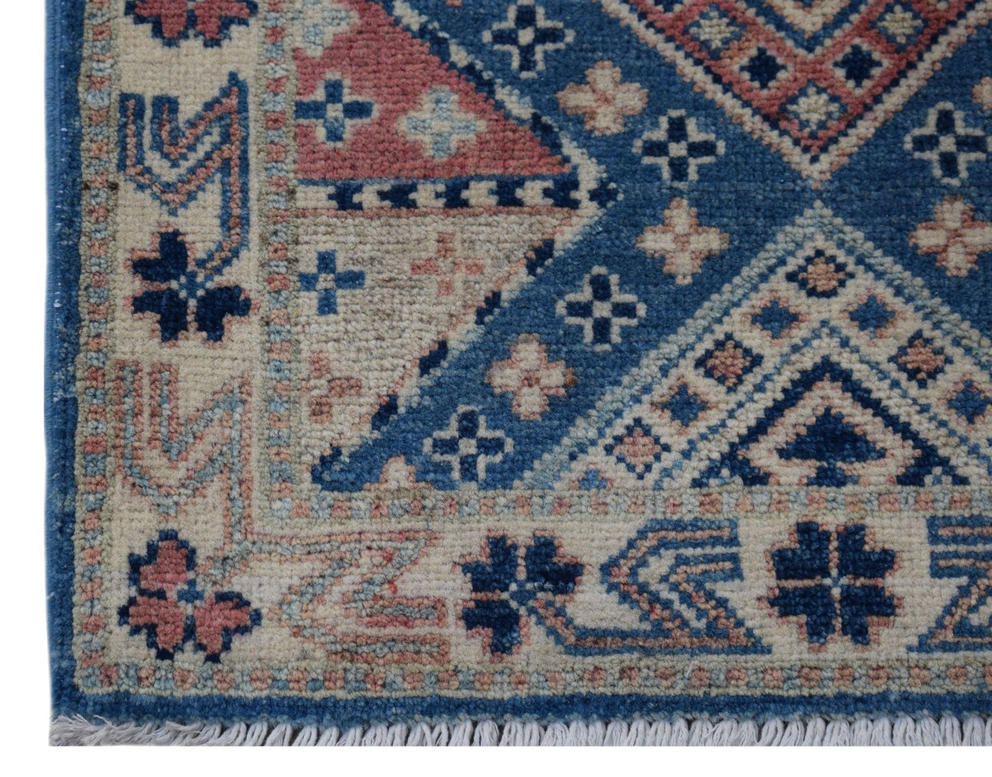 A handmade Afghan Kazakh rug featuring a geometric blue, cream, and pink pattern with fringe.
