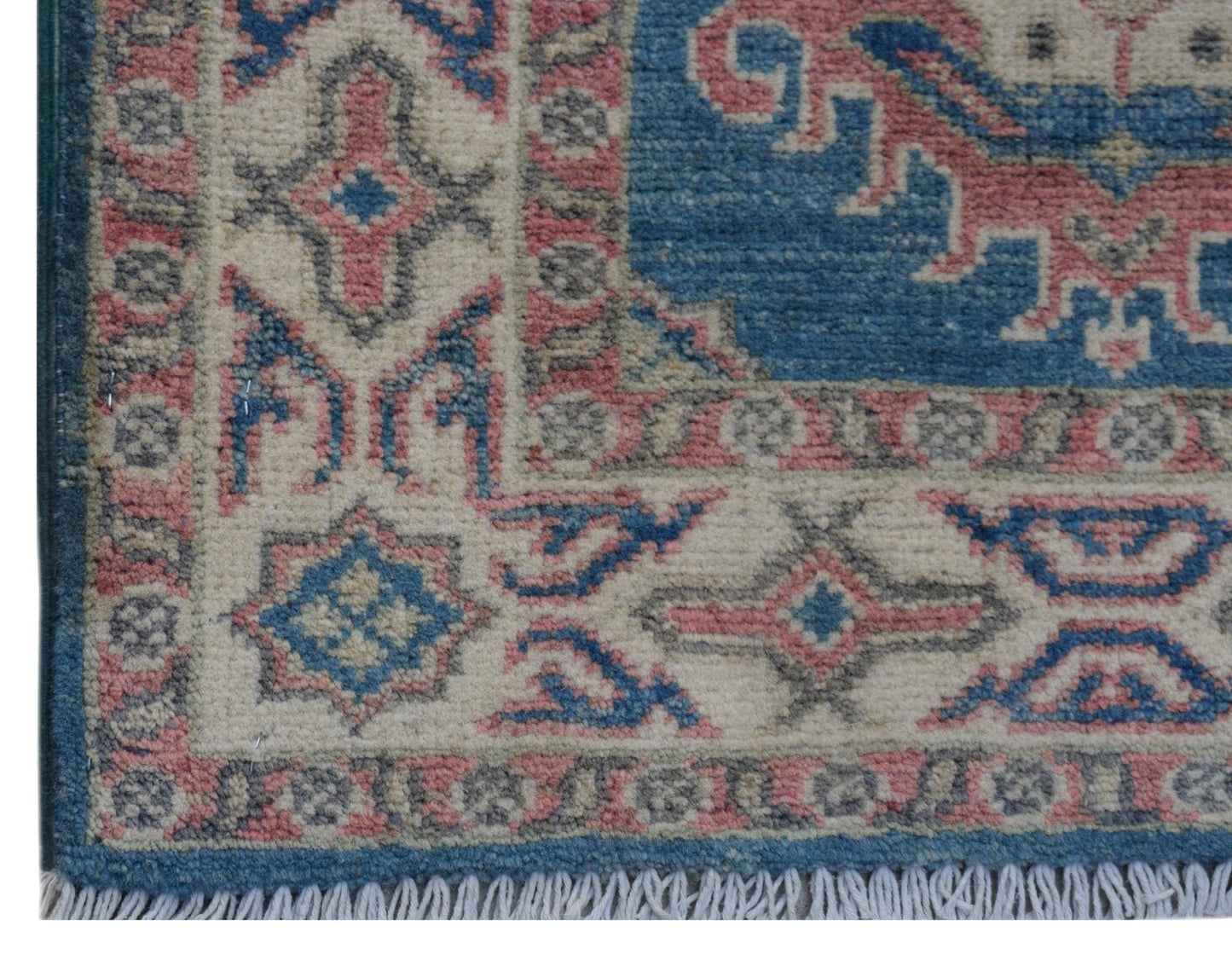 A handmade wool Afghan Kazakh rug featuring a geometric pattern in blue, pink, and cream tones.