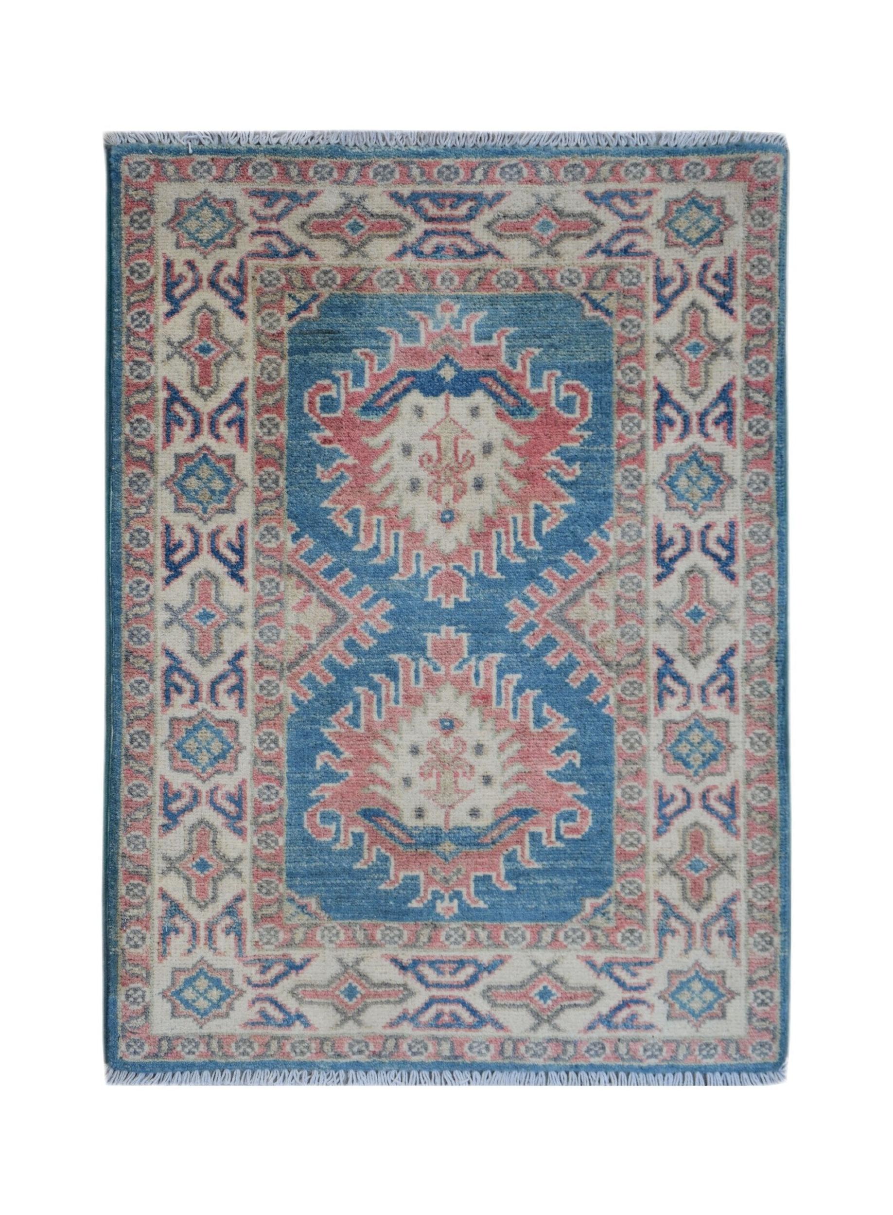 A handmade wool Afghan Kazakh rug featuring a blue field with pink and cream geometric medallions.
