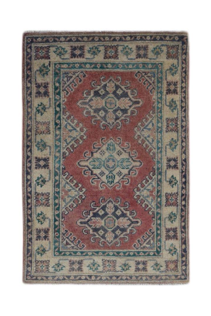 A handmade wool Afghan Kazakh rug featuring a red field with three geometric medallions.
