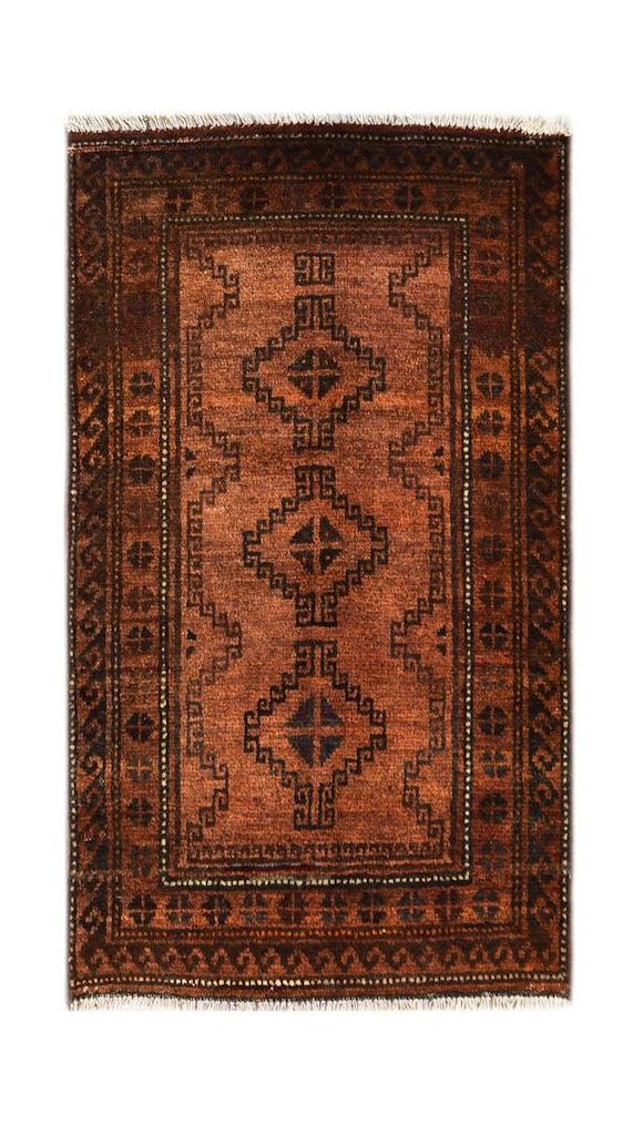 A handmade vintage Afghan Baluch rug featuring geometric diamond motifs in shades of brown and red.