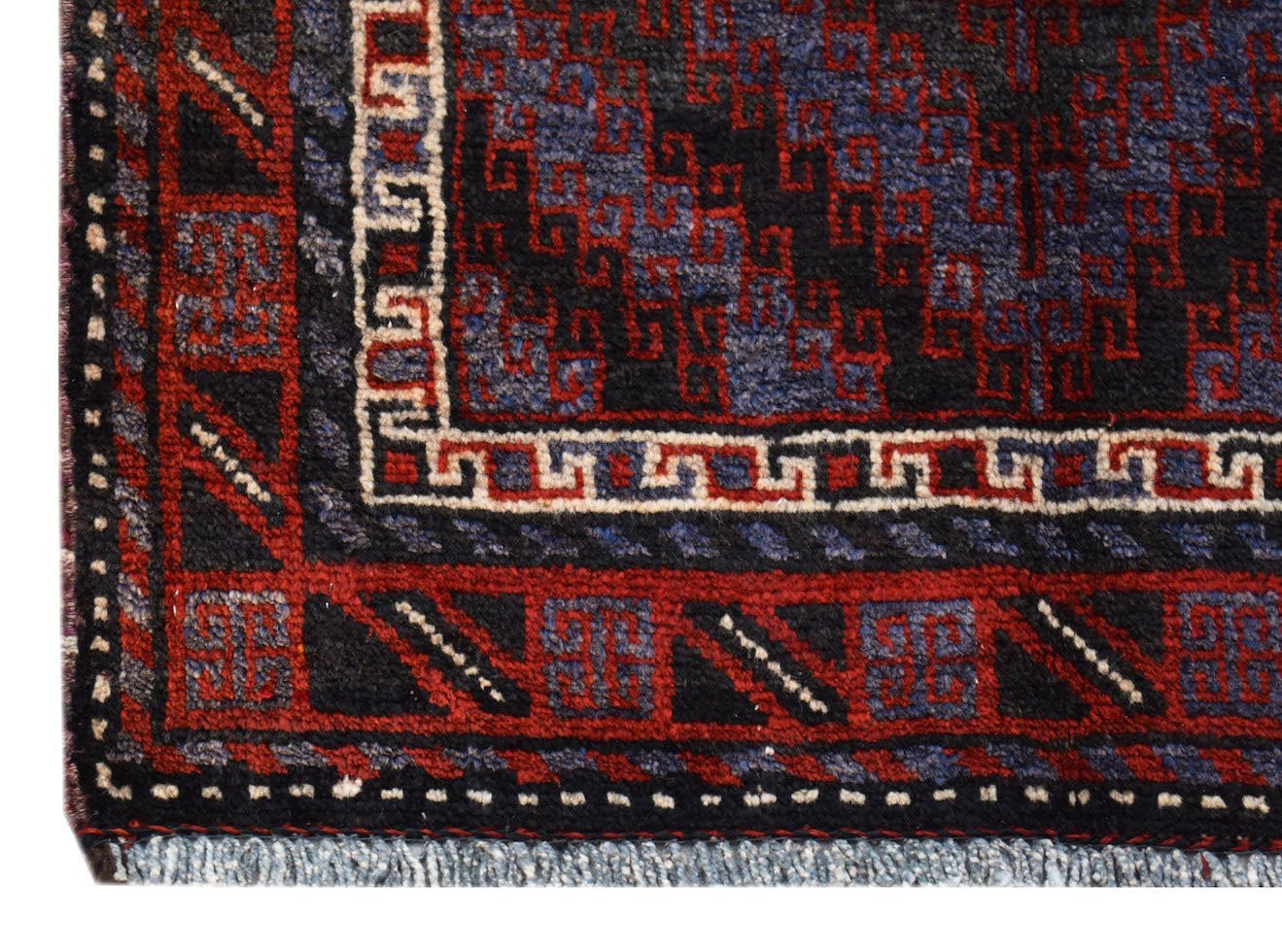 A vintage Afghan Baluch rug featuring geometric patterns in dark red, blue, and ivory wool.