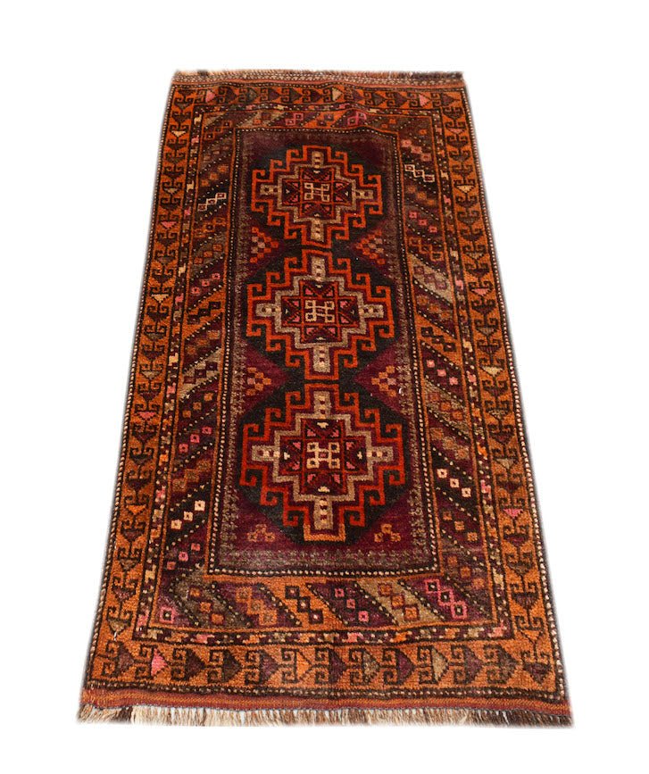 A vintage Afghan Baluch rug featuring three geometric medallions in shades of red and brown.