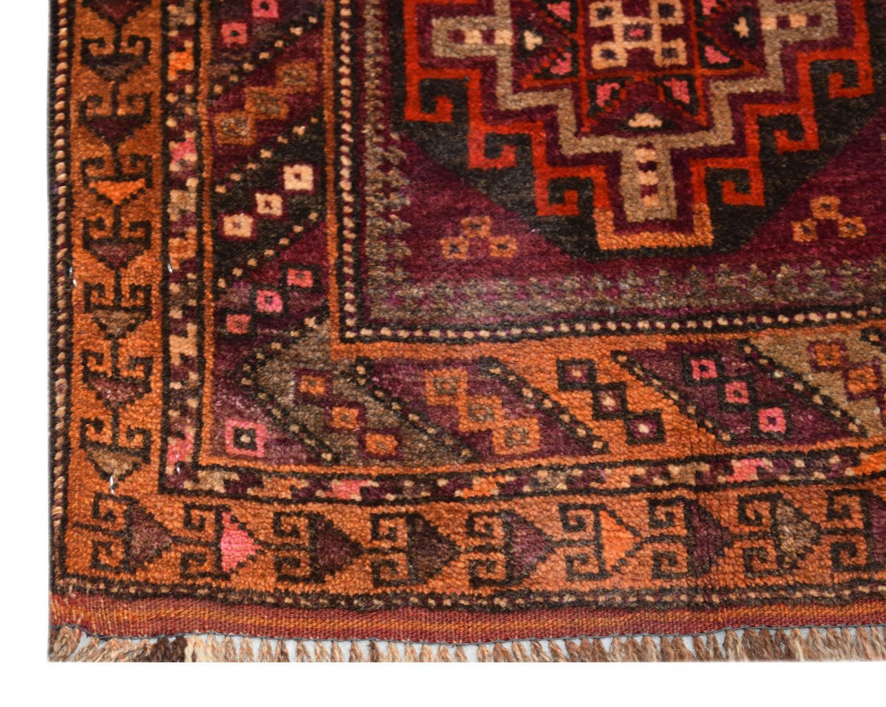 A vintage handmade Afghan Baluch rug featuring geometric patterns in shades of orange and burgundy.