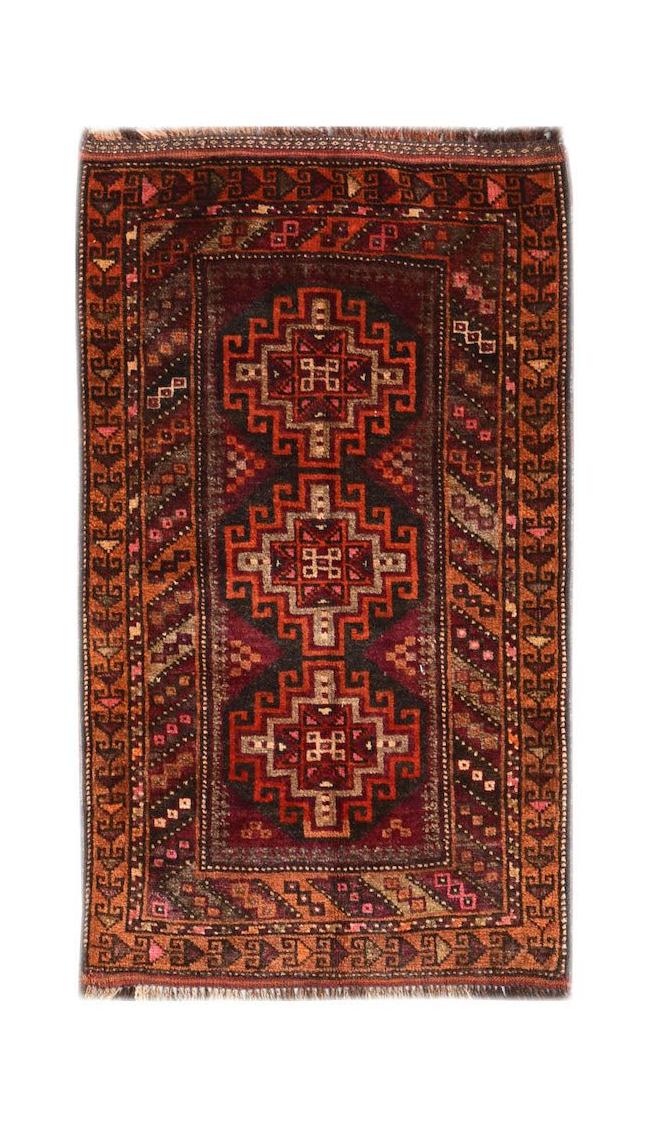 A vintage Afghan Baluch rug featuring three geometric medallions in shades of red and brown.