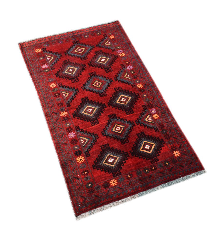 A vintage handmade Afghan Baluch rug featuring a red field with repeating diamond motifs.